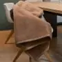 Lichtbruine knuffelzachte deken uitgespreid over een stoel