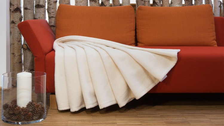 Pluche deken in een lichte natuurtint uitgespreid op een bank
